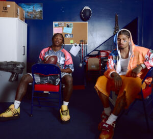 Alvin Kamara and Marcus Allen wearing PDF’s SS25 collection, including layered tops and structured trainers, on a football field