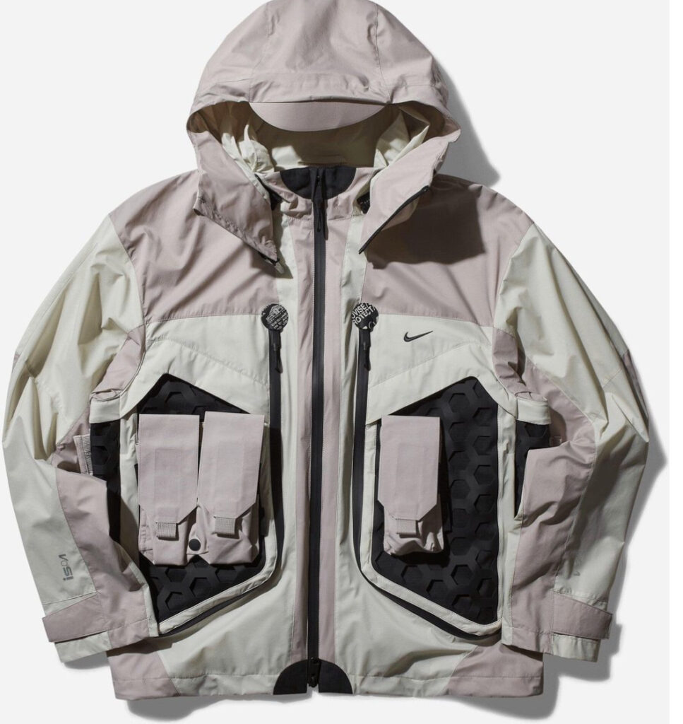 Nike ISPA Butterfly Jacket “Bone” in ripstop nylon with removable sleeves and split-back design, styled against concrete backdrop