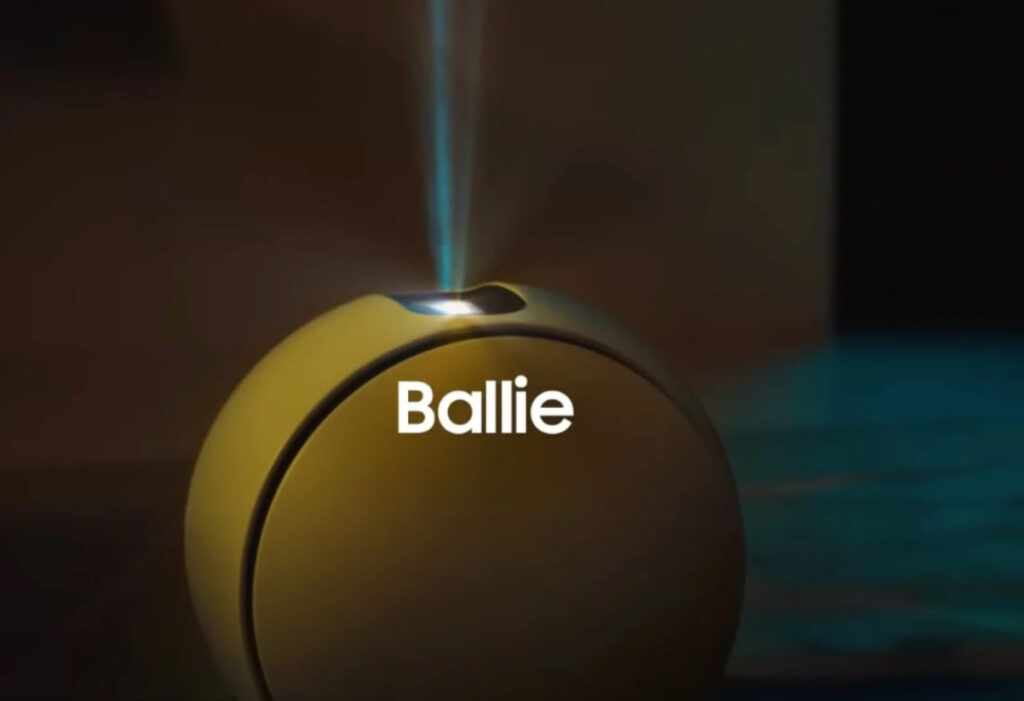 Samsung Ballie robot assistant rolling on hardwood floor, projecting media onto nearby wall