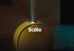 Samsung Ballie robot assistant rolling on hardwood floor, projecting media onto nearby wall
