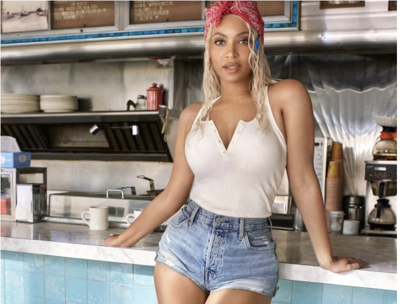 Beyoncé in vintage Levi’s jeans standing behind the counter of a sunlit roadside diner in the “Refrigerator” campaign