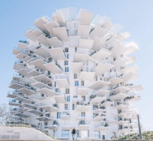L’Arbre Blanc tower in Montpellier, France, featuring cantilevered balconies resembling tree branches against a blue sky