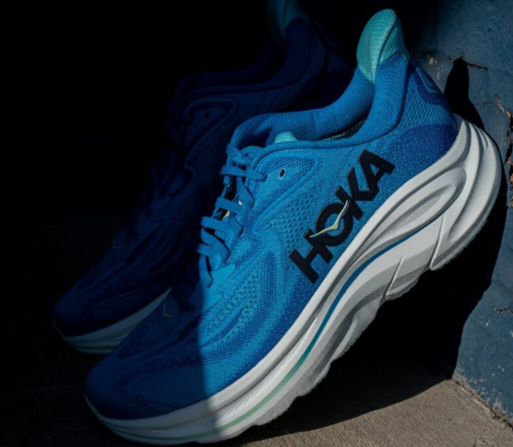 HOKA Clifton 10 running shoe featuring jacquard upper and cushioned foam midsole in soft blue and lime green colorway