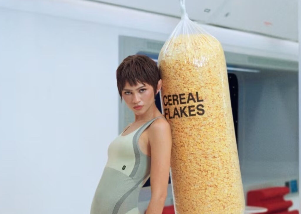 Zendaya wears a seamless Studio Knit Bodysuit in olive green, punching a cereal-filled boxing bag in On’s surreal “Zone Dreamers” campaign