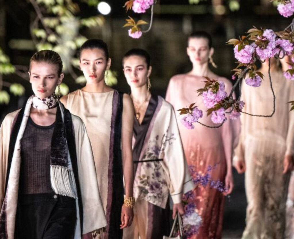 Model in Dior Fall 2025 embroidered cape walks through Kyoto’s To-ji Garden at twilight, pagoda lit in background