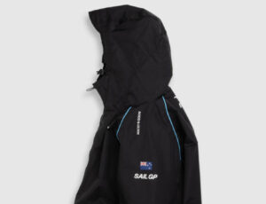Rodd & Gunn Cosair Bay Jacket featuring articulated hood, chunky zip, and SailGP sponsor branding, worn outdoors in wind