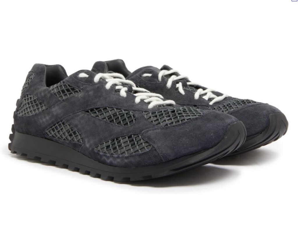 Bottega Veneta Orbit shoe in silver and lime, placed on a concrete pedestal with soft lighting, highlighting its sculpted sole