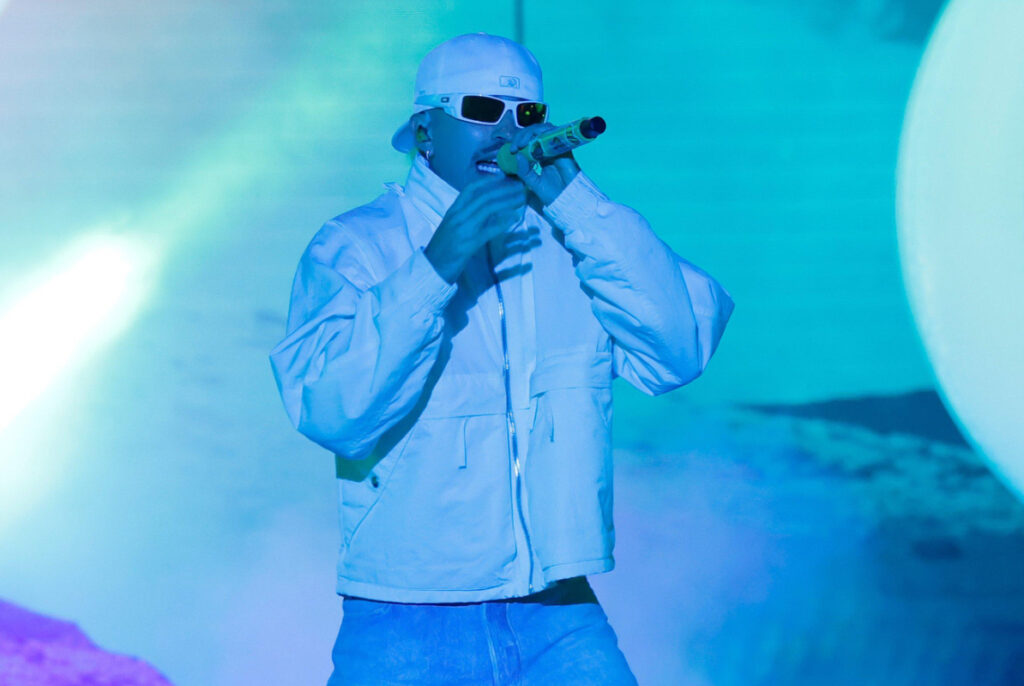 Feid performs on the COLORS stage with a light blue hue-lit backdrop, standing confidently with a mic, immersed in his live debut