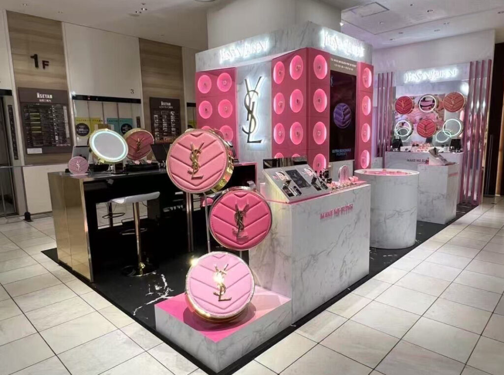 Gold-accented YSL visual merchandising prop with faux leather texture, spotlighting a handbag in a high-end retail setting