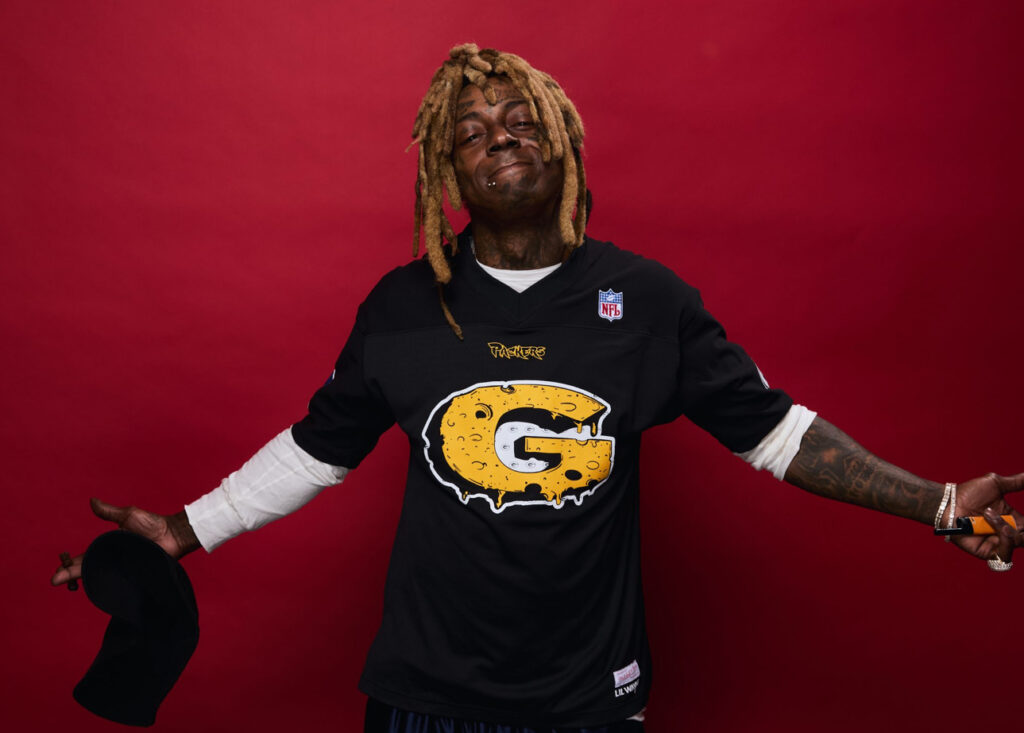 Lil Wayne wearing the Carter VI Packers jersey from his 2025 NFL Draft collection with Mitchell & Ness, standing in front of Lambeau Field