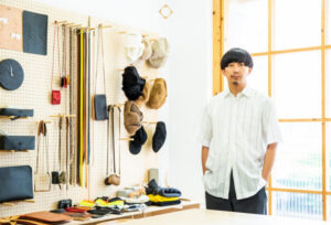 Interior of Hender Scheme’s Tokyo atelier showing leather tools, a cobbler bench, and artisan footwear in soft lighting