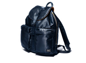 PORTER Tanker Rucksack in Iron Blue, showcasing lustrous nylon twill and minimalist design, photographed against urban backdrop