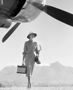 Wenda Parkinson in a grey Dorville gabardine dress beside a Hermes airplane, photographed by Norman Parkinson in Nairobi, 1951
