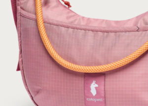 The Trozo Shoulder Bag featuring an adjustable climbing rope strap, resting on a bench during a casual weekend outing