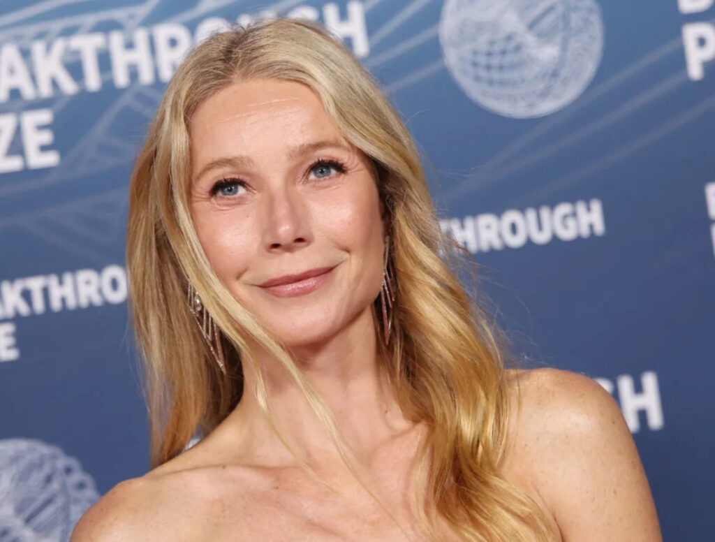 Gwyneth Paltrow smiling with a slice of sourdough bread, symbolizing her move away from restrictive clean eating