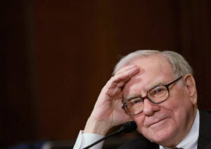 Warren Buffett stands at the podium inside CHI Health Center Omaha during his final Berkshire Hathaway shareholder meeting