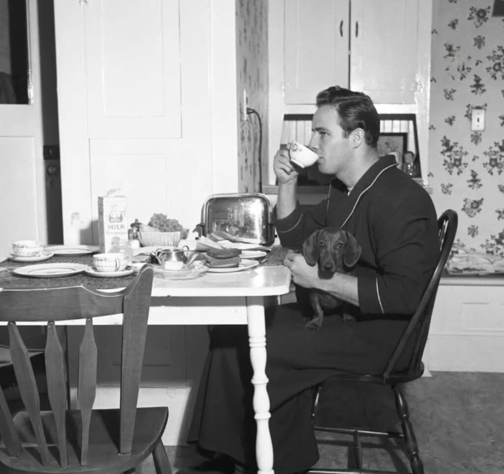 Black-and-white photo of young Marlon Brando at breakfast in his California home, 1949—seated at a table in natural light