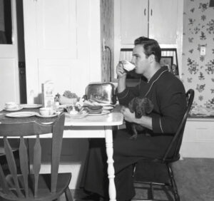 Black-and-white photo of young Marlon Brando at breakfast in his California home, 1949—seated at a table in natural light
