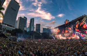 Crowd dancing under fireworks at Ultra Music Festival 2025 in Miami, with city skyline and main stage lights in the background