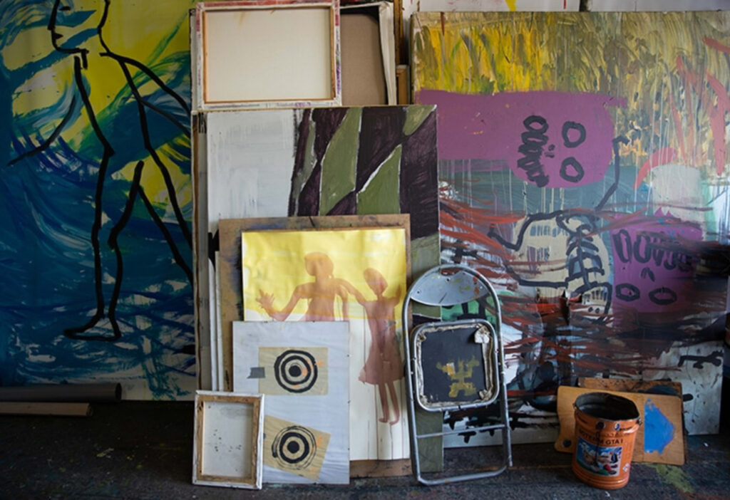 studio surrounded by abstract and mixed-media artworks