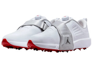 Side view of the Jordan Air Rev Golf Shoe in white with metallic silver accents, placed on a green golf course fairway