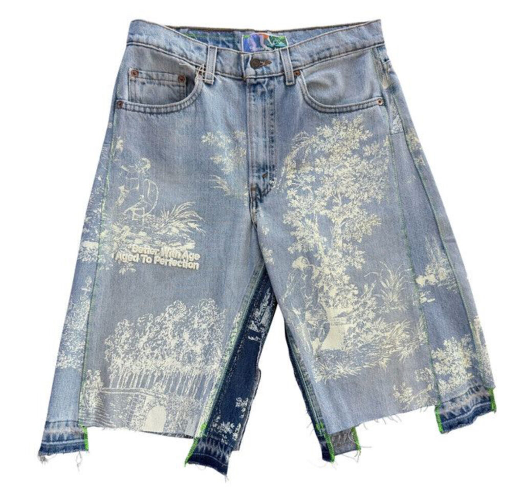 Older woman wearing double-wide indigo denim shorts, standing confidently with sun-faded fabric and frayed edges