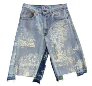 Older woman wearing double-wide indigo denim shorts, standing confidently with sun-faded fabric and frayed edges