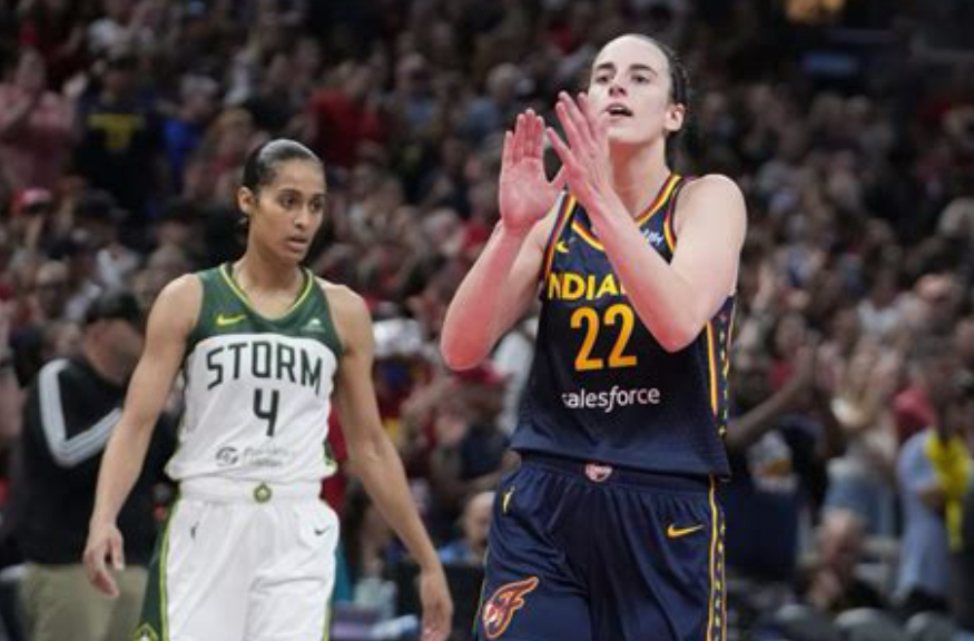 Caitlin Clark dribbling past defenders during a WNBA game, showcasing her scoring and playmaking dominance