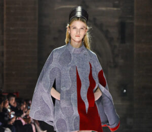 Model in metallic gown from Louis Vuitton Cruise 2026 walking through the gothic arches of Palais des Papes