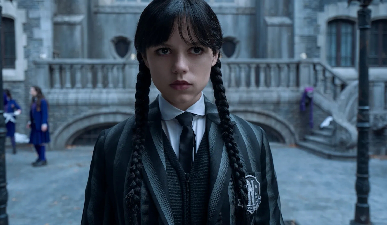 Jenna Ortega as Wednesday Addams, dressed in black with braids and a cold stare, symbolizing the commercialization of rebellion
