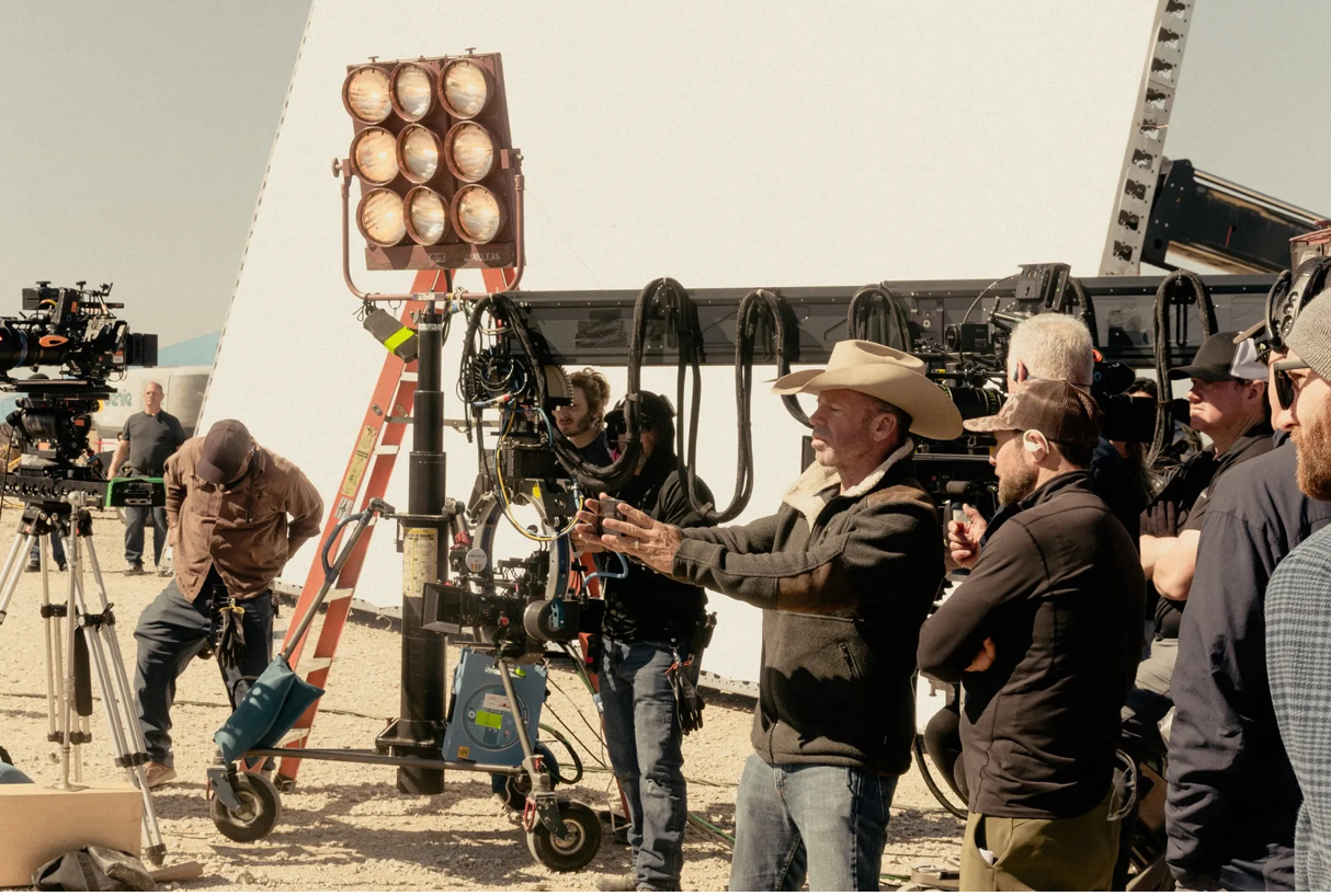 Film crew in desert landscape with Texas flag backdrop