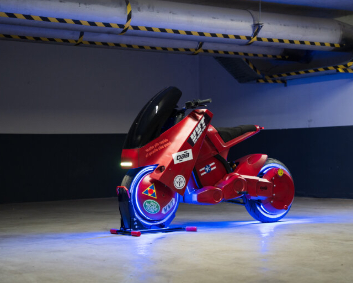 3D-printed electric motorcycle in matte red with anime-inspired design, created by DAB Motors and VVT, echoing Akira