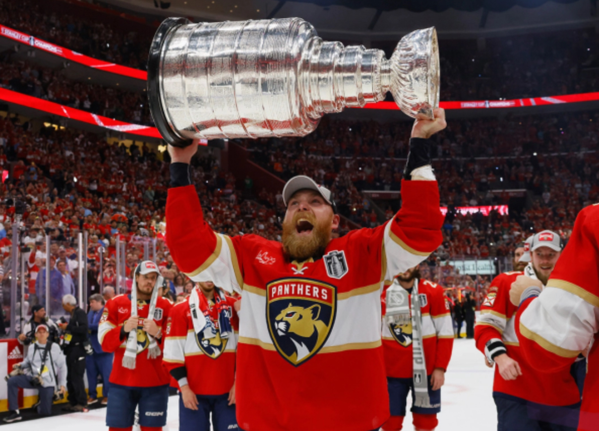 Florida Panthers player lifting the Stanley Cup surrounded by teammates after winning the NHL championship
