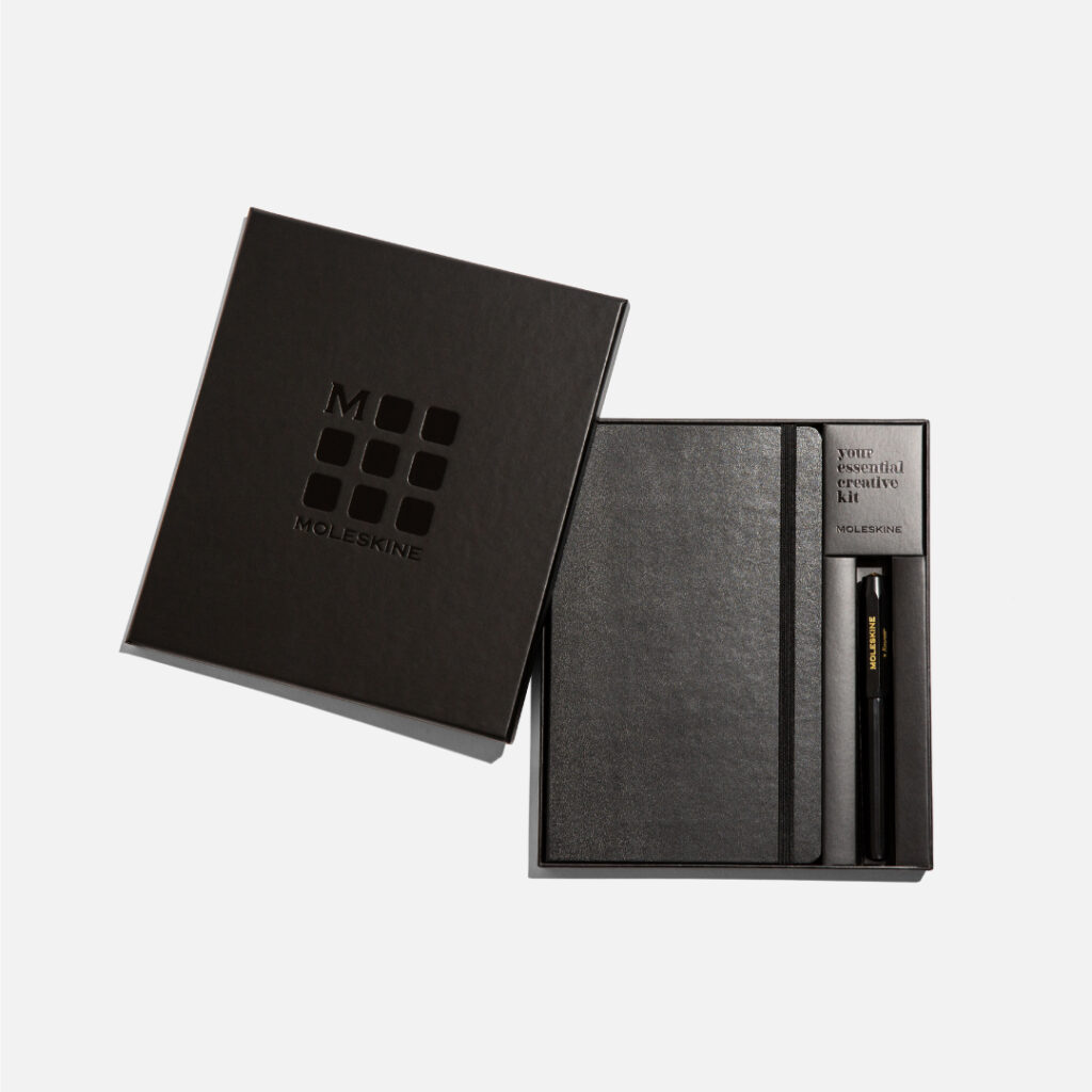 Moleskine “The Classic” Essential Kit featuring a black notebook and pen in an elegant gift box, viewed from above