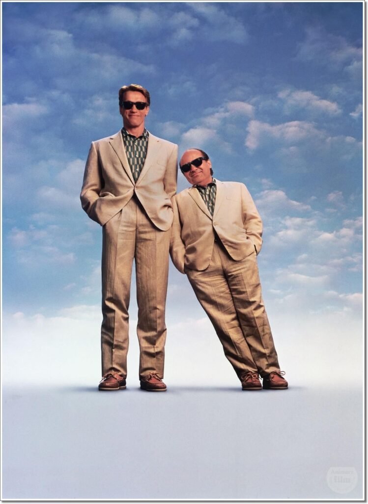 Poster for Twins (1988) showing Arnold Schwarzenegger and Danny DeVito in matching beige suits and sunglasses, standing against a cloudy blue sky. DeVito leans against the much taller Schwarzenegger, emphasizing their comedic contrast as twin brothers