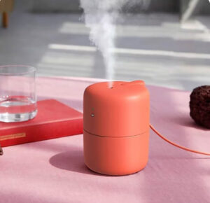 Minimal USB desktop humidifier emitting mist on a modern wooden desk setup