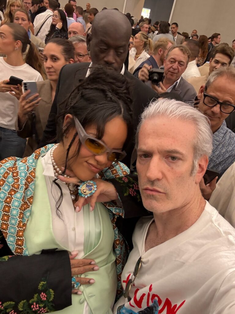 Rihanna at Jonathan Anderson’s Dior debut wearing a mint waistcoat and embroidered jacket, posing in a vibrant crowd