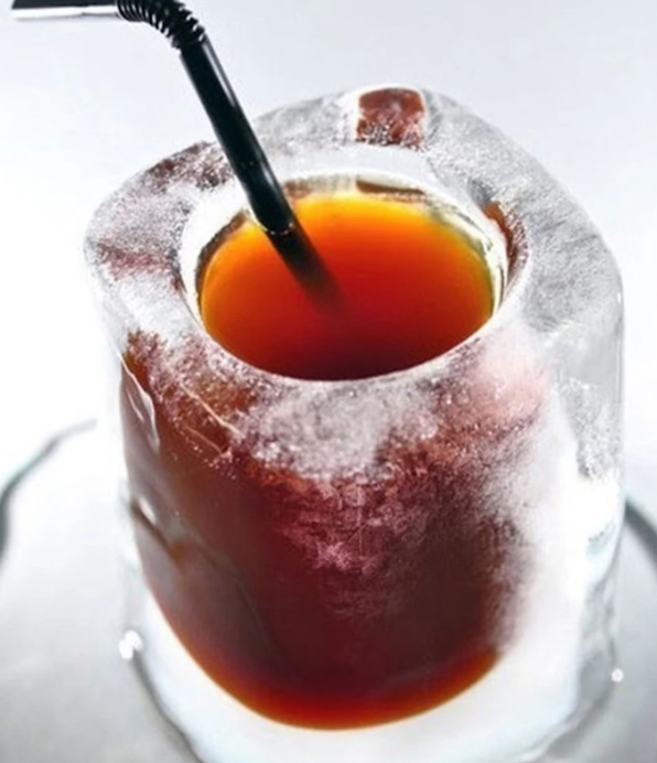 Close-up of a drink served in an ice shot glass with a black straw, made using a silicone shot glass ice cube mold