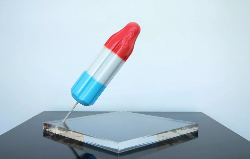 Sculptural artwork of a red, white, and blue Bomb Pop-style popsicle by Derrick Adams, angled on a clear acrylic base