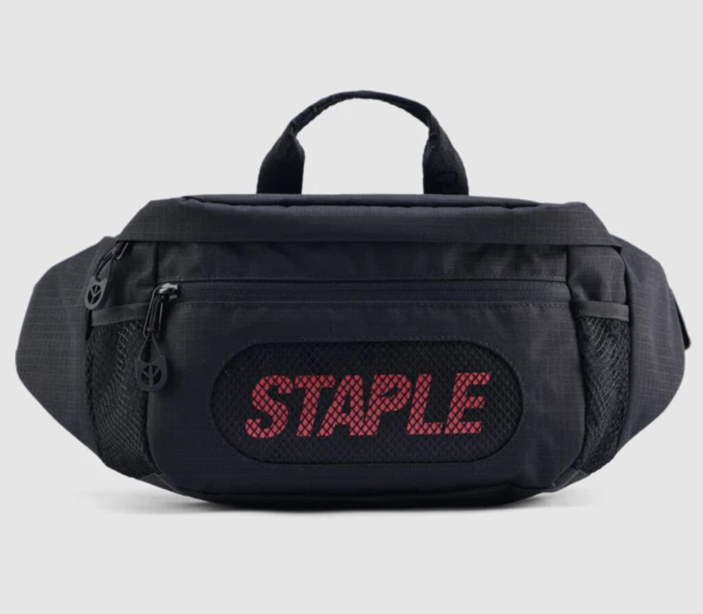 Staple Pigeon logo waist bag displayed on a concrete backdrop, styled crossbody with urban streetwear outfit