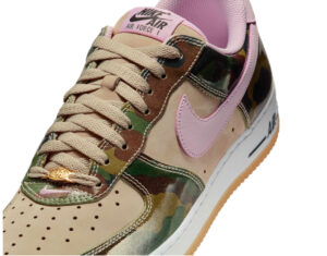 Nike Air Force 1 Low shoe featuring a pink camouflage Swoosh and white leather upper with light gum sole