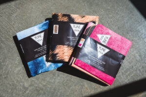 Three Foldable pink Yune Yoga Apollo travel yoga mat unfolded and folded, showing compact 2mm structure on flat surface