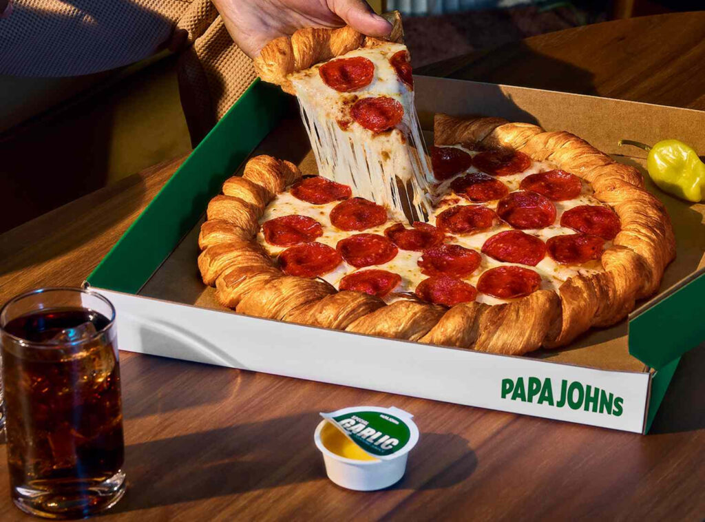 Papa John’s Croissant Pizza with golden, flaky crust and melted cheese, topped with pepperoni and served in a custom delivery box