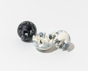 A pair of O SKIN&HAIR Relaxation Balls—one fully closed with a black-and-white marbled exterior, and the other open to reveal a spiked, soft inner surface designed for tactile massage therapy