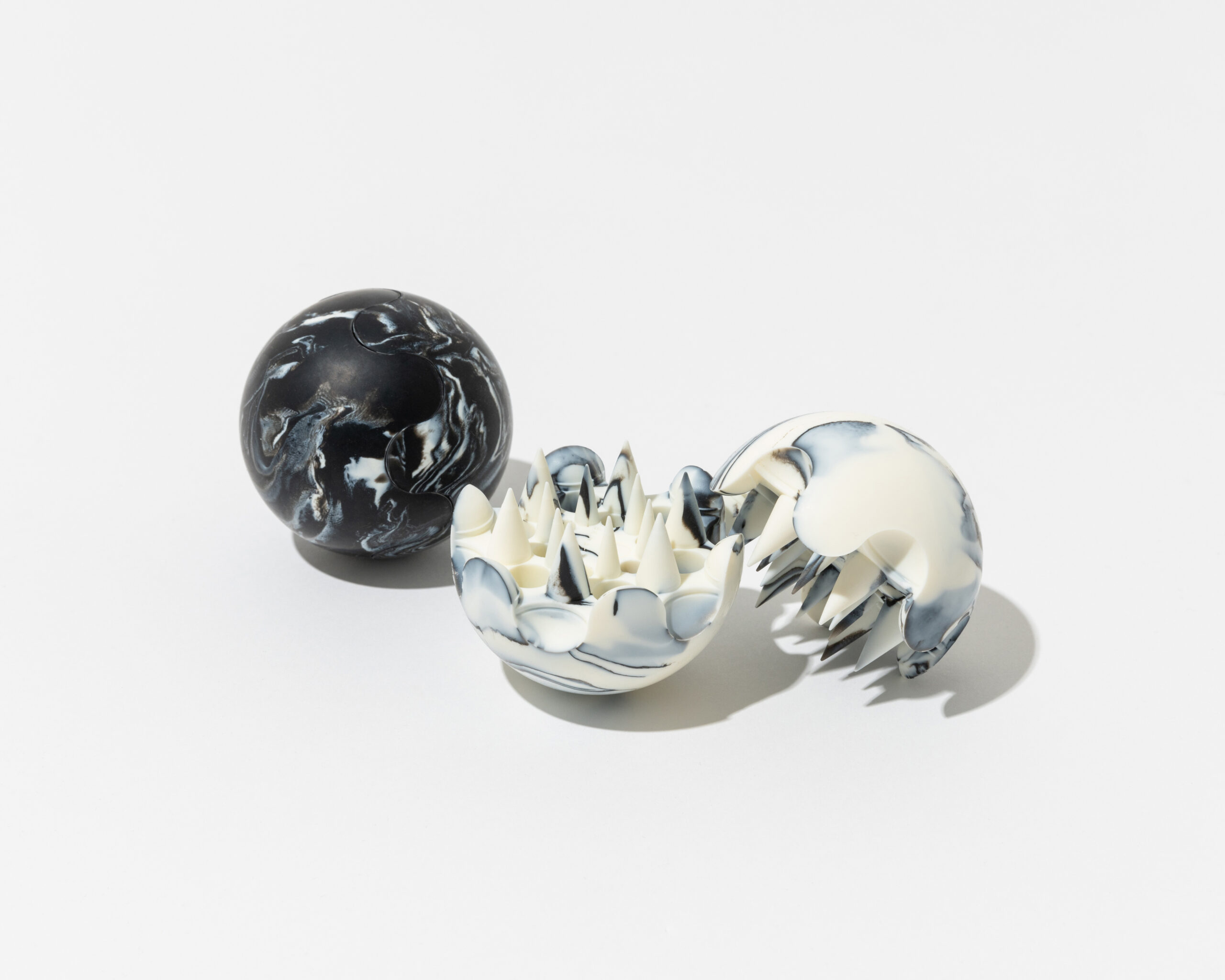 A pair of O SKIN&HAIR Relaxation Balls—one fully closed with a black-and-white marbled exterior, and the other open to reveal a spiked, soft inner surface designed for tactile massage therapy