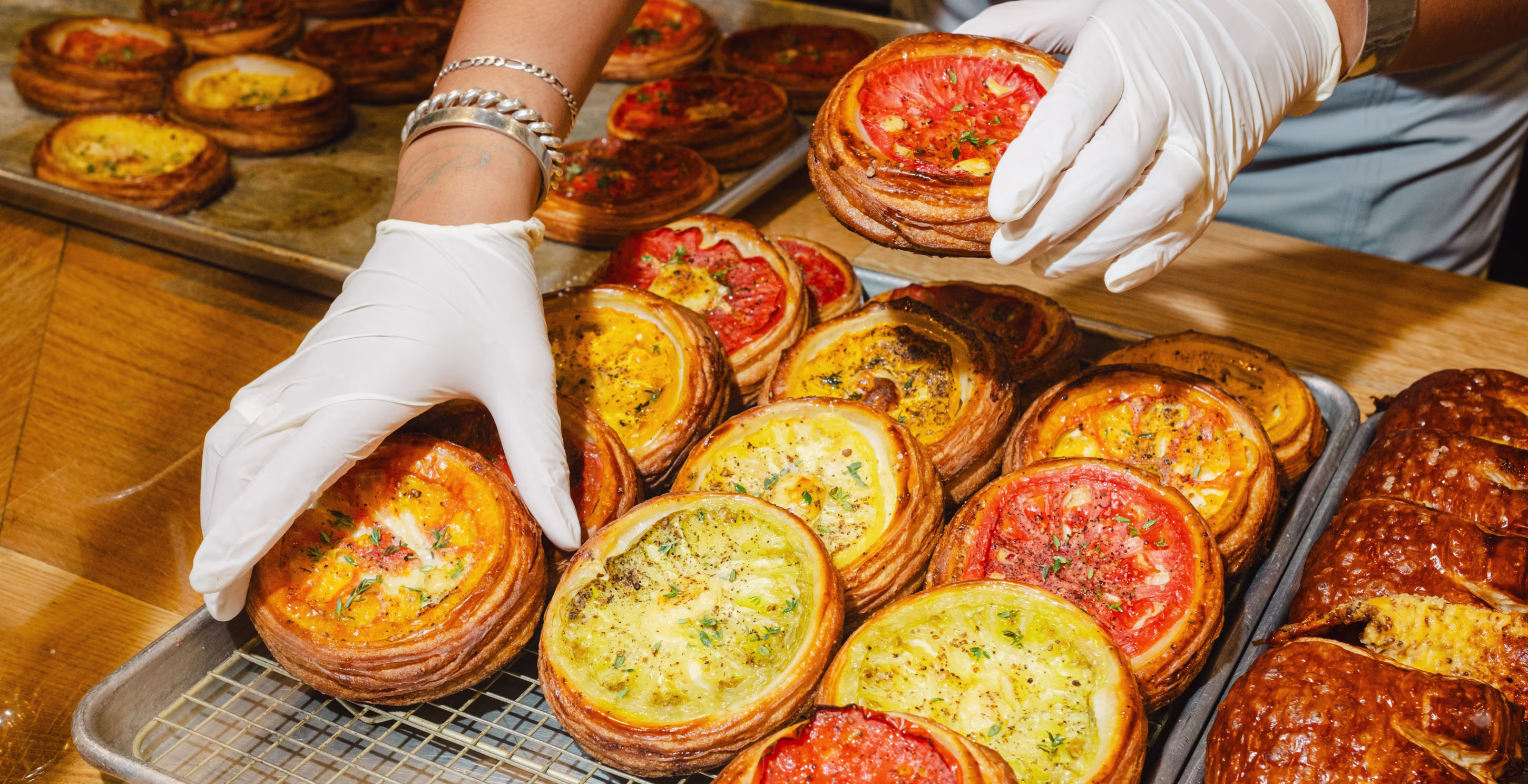A display of savory bakery items including ham-filled croissants, cheese scones, and egg galettes on a wooden counter