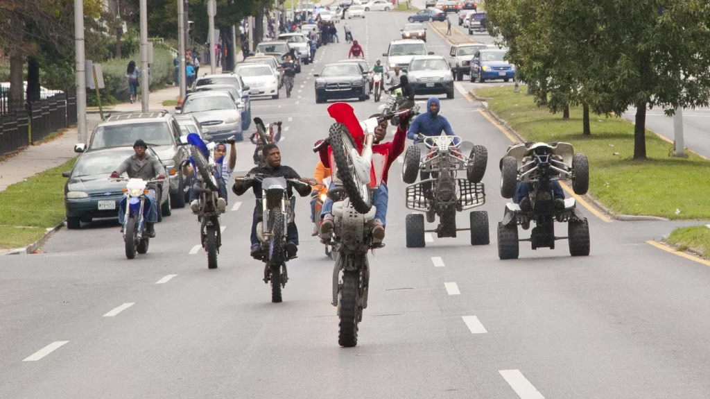 Hundreds of Baltimore bikelife riders perform wheelies through city streets under hovering police helicopters and flashing sirens
