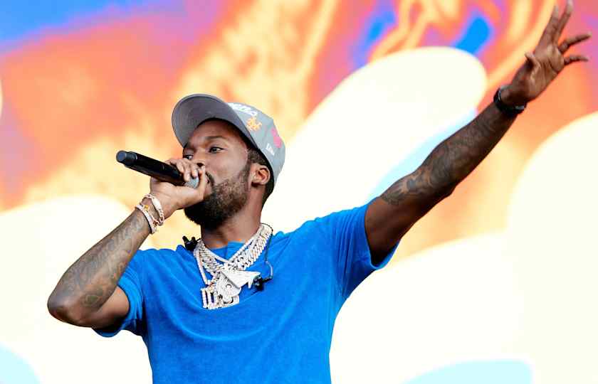 Meek Mill standing on stage at Roots Picnic 2025, wearing a Phillies hat, with fans cheering in Philadelphia
