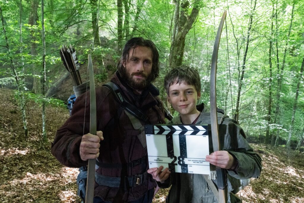 a behind the scene snap shot of Alfie Williams from trailer holding a film clapperboard