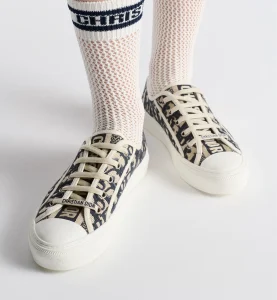 Close-up of a pair of Walk'n'Dior shoes in deep blue Dior Oblique embroidered cotton, worn with white mesh Dior socks, highlighting the signature "Christian Dior" details